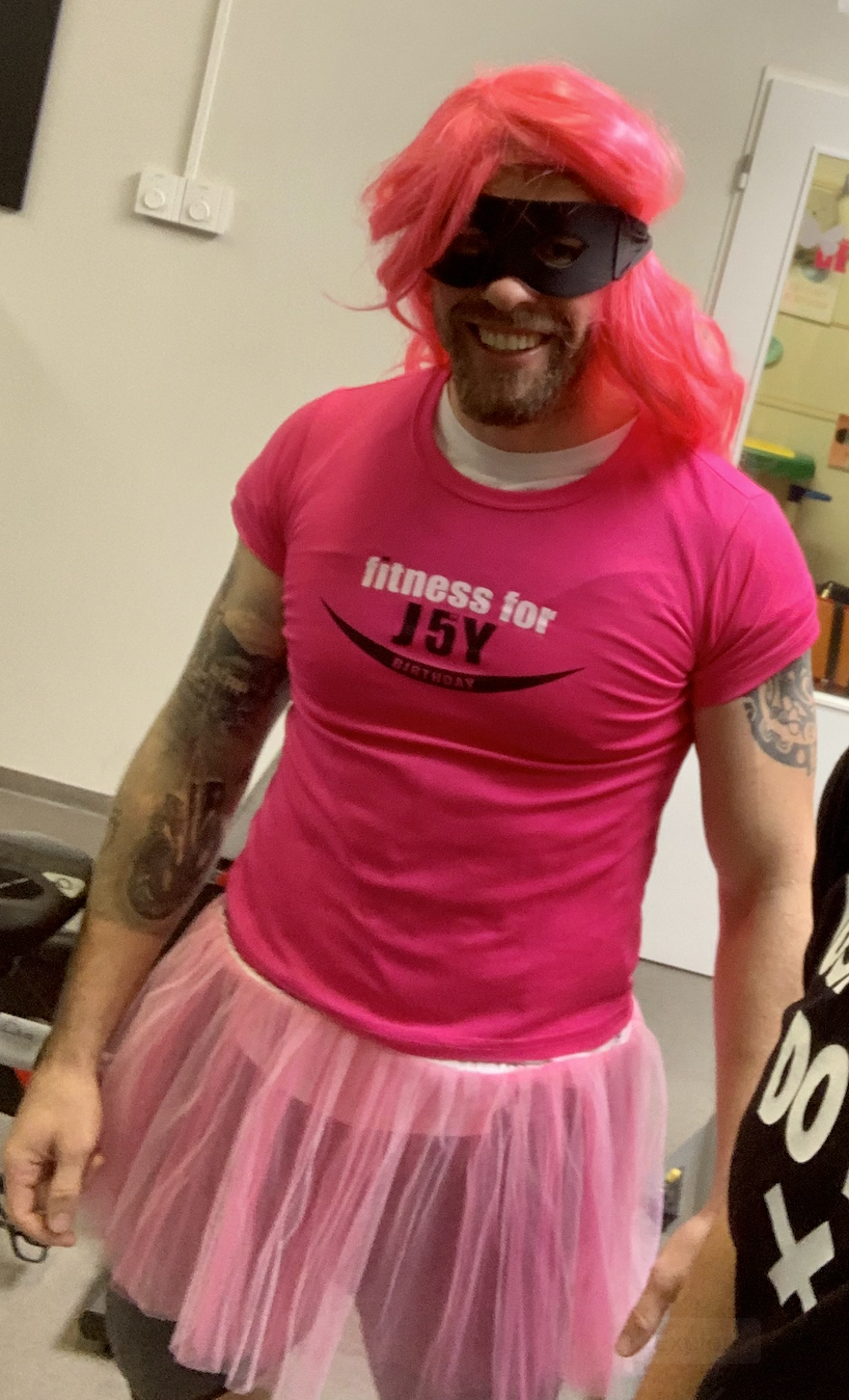 Muž v růžovém kostýmu s tutu sukní a paruce