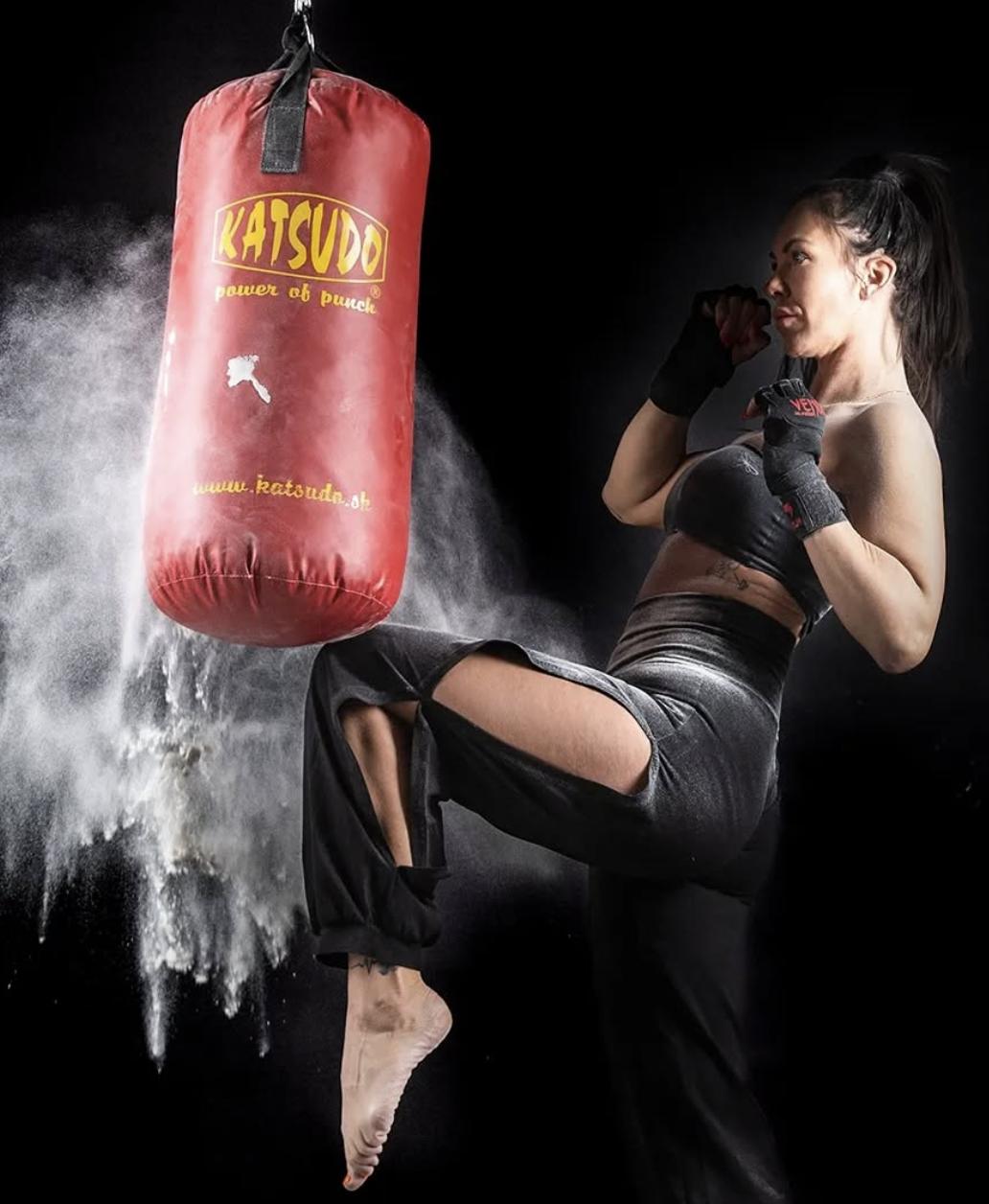 Žena při intenzivním kickboxu s boxovacím pytlem