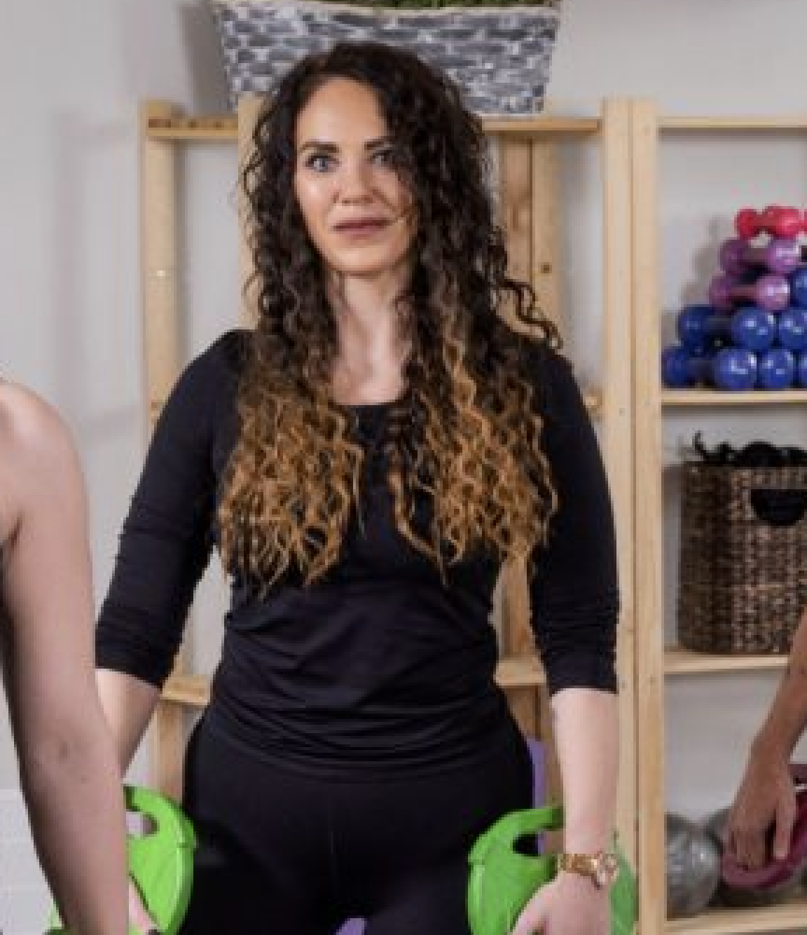 Žena s kudrnatými vlasy ve fitness studiu